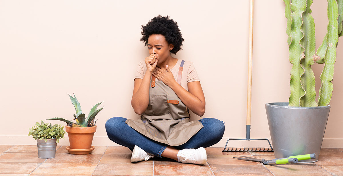 Gardener woman sitting on the floor is suffering with cough and feeling bad