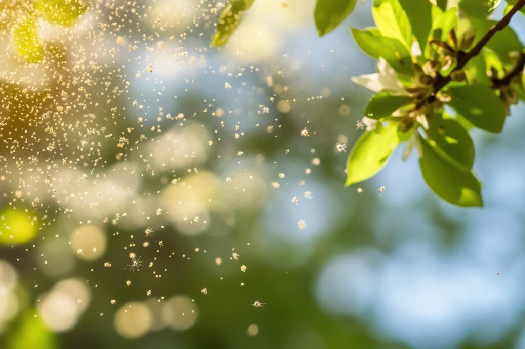 Pollen particles floating in sunlit air with green leaves